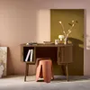 A wooden desk with a stool in front of it, set against a two-toned wall. Produktbild-Vorschau