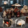 A detailed wooden model of a steam tractor with a trailer of barrels, set on a gravel surface. Produktbild-Vorschau