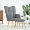 A gray fabric armchair and ottoman are shown in a well-lit room with a large plant and a floor lamp. Náhľad obrázku produktu