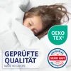 A child sleeping under a white duvet, with marketing logos and text overlaid. Produktbild-Vorschau