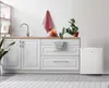A clean, modern kitchen counter with a sink, faucet, some fruit, a plant, and a mini-refrigerator. Voir les images du produit