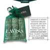 A green mesh bag containing three bundles of white sage, with a small card also featuring the brand logo. Produktbild-Vorschau