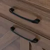 A close-up view of two black drawer pulls on a wooden cabinet. Podgląd zdjęcia produktu