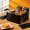 A double deep fryer with french fries and chicken nuggets inside, set on a wooden table. Produktbild-Vorschau