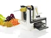A spiralizer with a potato being cut into spirals, next to a plate of spiralized vegetables. Produktbild-Vorschau