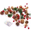 A string of Christmas lights featuring pinecones, artificial pine branches, and red berries, with a battery pack visible. Produktbild-Vorschau