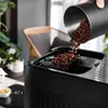 Coffee beans being poured into a coffee machine. Produktbild-Vorschau