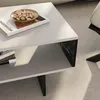 A close-up view of a modern white coffee table with a marble black accent and a small bowl of pistachios on top. Anteprima dell’immagine prodotto