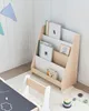 A child's bookshelf filled with books, next to a small chair and a chalkboard table. Náhled obrázku produktu