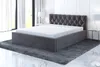 A modern bedroom setting with a gray upholstered bed and mattress. Produktbild-Vorschau