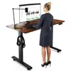 A woman is standing at a height-adjustable desk, using a computer. Náhled obrázku produktu