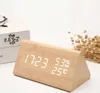 A wooden digital clock displaying time, humidity, and temperature, placed on a white surface next to books and dried flowers. Produktbild-Vorschau