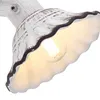 A close-up view of a white ceramic spotlight with a scalloped edge, showing the light bulb inside. Produktbild-Vorschau