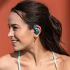 A woman wearing teal earbuds, smiling, with an orange background. Anteprima dell’immagine prodotto
