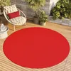 A round red rug on a wooden deck with a chair and plants. Náhled obrázku produktu