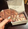 A hand holding several small packets of cream, with a box of the product in the background. Náhľad obrázku produktu
