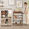 A woman is pushing a kitchen cart in a room with artwork on the wall. Podgląd zdjęcia produktu