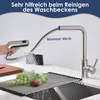A kitchen faucet with a pull-out spray head is shown demonstrating its reach over a sink with a roll-up drying rack and grapes. Podgląd zdjęcia produktu