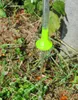 Water is flowing from a green shower head into grass. Náhled obrázku produktu
