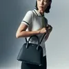 A woman is holding a black handbag. Anteprima dell’immagine prodotto