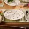 A table setting with a floral patterned plate, cutlery, and a glass of wine. Náhled obrázku produktu
