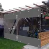 A transparent outdoor curtain with grommets and a zipper, attached to a wooden pergola structure, providing shelter and privacy for a patio area. Produktbild-Vorschau