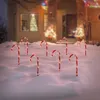 Christmas candy canes with lights in the snow in front of a house decorated for the holidays. Voir les images du produit