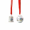 Two Christmas ornaments, a bell and a ball, hanging from red ribbons against a white background. Produktbild-Vorschau