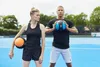 A man and a woman are standing on a blue court, holding medicine balls. Náhľad obrázku produktu