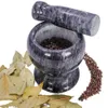 A marble mortar and pestle filled with peppercorns, with bay leaves and loose peppercorns scattered around it. Voir les images du produit