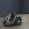 A vacuum cleaner is shown in an empty room with dark blue walls and a light gray floor. Voir les images du produit