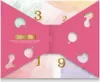 A pink advent calendar with cut-out shapes and gold numbers, designed to look like a bow tie. Náhled obrázku produktu