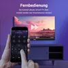A hand holding a smartphone displaying a TV remote app, with a TV screen in the background showing a video. Produktbild-Vorschau