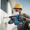 A construction worker is drilling a hole in a wall with a power drill. Produktbild-Vorschau