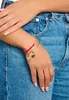 A close-up shot of a person's hand wearing multiple bracelets, with a focus on the charms. Náhled obrázku produktu