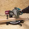 A person is using a miter saw to cut a piece of wood. Podgląd zdjęcia produktu