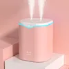 A pink humidifier with two streams of mist is displayed on a white pedestal, with pink blocks in the background. Náhled obrázku produktu