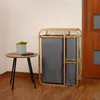 A laundry basket with three bags and a small side table with a plant and phone on a wooden floor. Produktbild-Vorschau