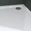 A close-up view of a white shower tray with a textured surface and a chrome drain. Produktbild-Vorschau