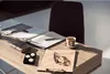 A desk with a notebook, pen, coffee cup, glasses, and a small black box with three orange tea lights. Náhľad obrázku produktu