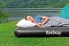 A woman sleeping on an air mattress next to a lake and a tent. Náhled obrázku produktu