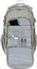 The image shows the open front compartment of a gray backpack with a white abstract pattern. Inside the compartment are various items, including a smartphone, charging cables, a wall adapter, and three markers (red, green, and black). Produktbild-Vorschau