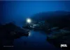 A person holding a headlamp in a dark, foggy, rocky environment near water. Náhľad obrázku produktu