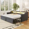 A dark gray upholstered daybed is shown in a well-lit room with large windows and a rug. Voir les images du produit