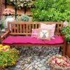 A wooden garden bench with cushions and decorative pillows, surrounded by plants and autumn decorations. Náhled obrázku produktu