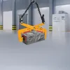 A heavy-duty clamp holding a stone block, suspended by chains in what appears to be a warehouse or industrial setting. Náhled obrázku produktu