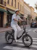 A man rides an electric bike down a street in a European town. Produktbild-Vorschau