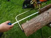 A person is measuring a log with a tape measure, with a chainsaw stand and holder in the background. Náhled obrázku produktu