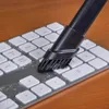 A close-up shot of a vacuum cleaner brush head cleaning a computer keyboard. Produktbild-Vorschau