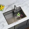A stainless steel kitchen sink with a faucet, a drying rack with apples and grapes, and a bowl of lemons and limes on a marble countertop. Podgląd zdjęcia produktu